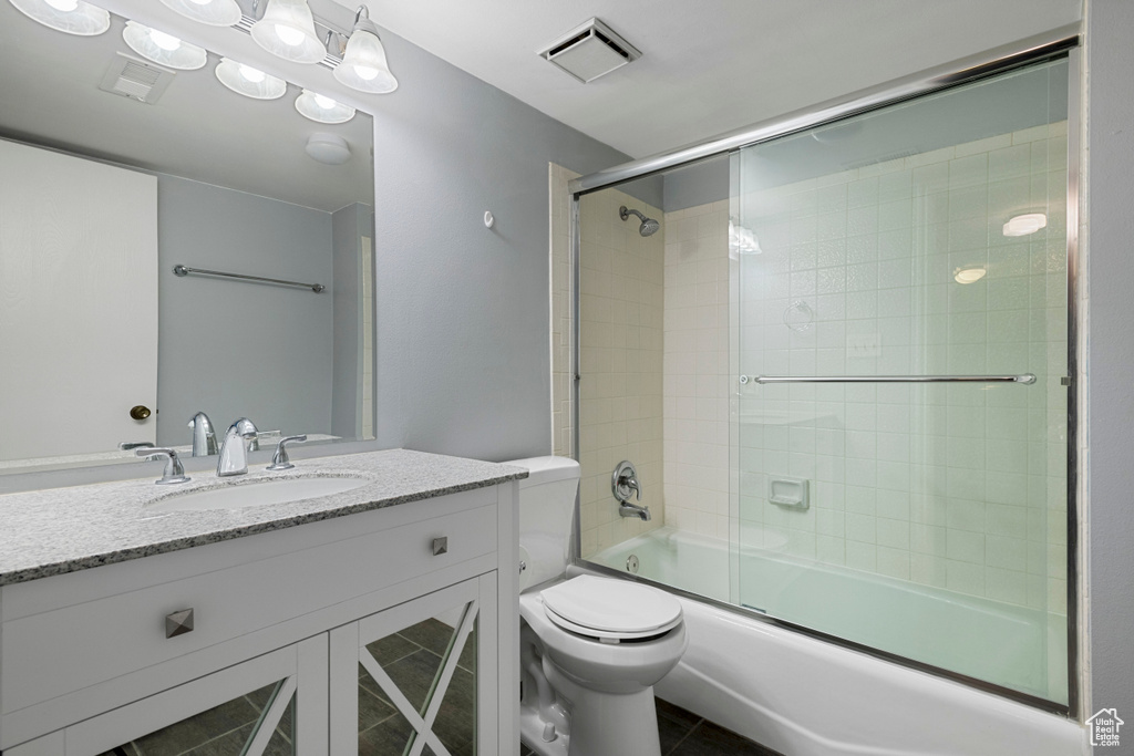 Bathroom with visible vents, tile patterned flooring, vanity, toilet, and combined bath / shower with glass door