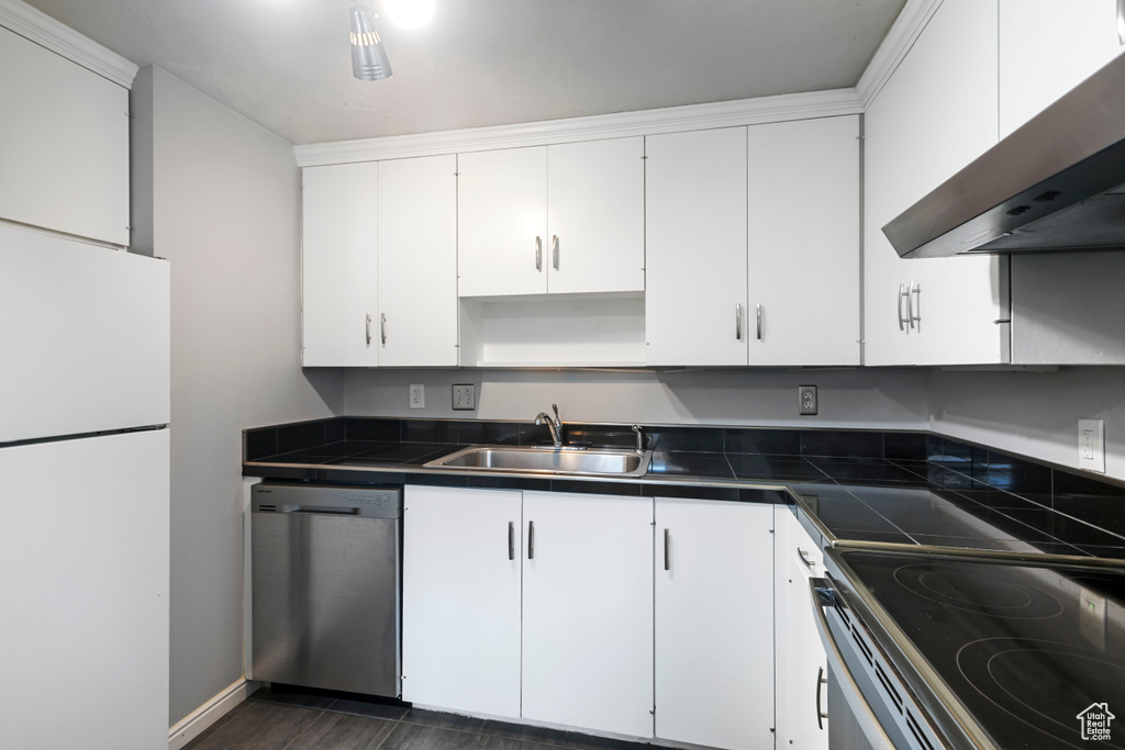 Kitchen featuring wall chimney range hood, a sink, electric range oven, freestanding refrigerator, and stainless steel dishwasher