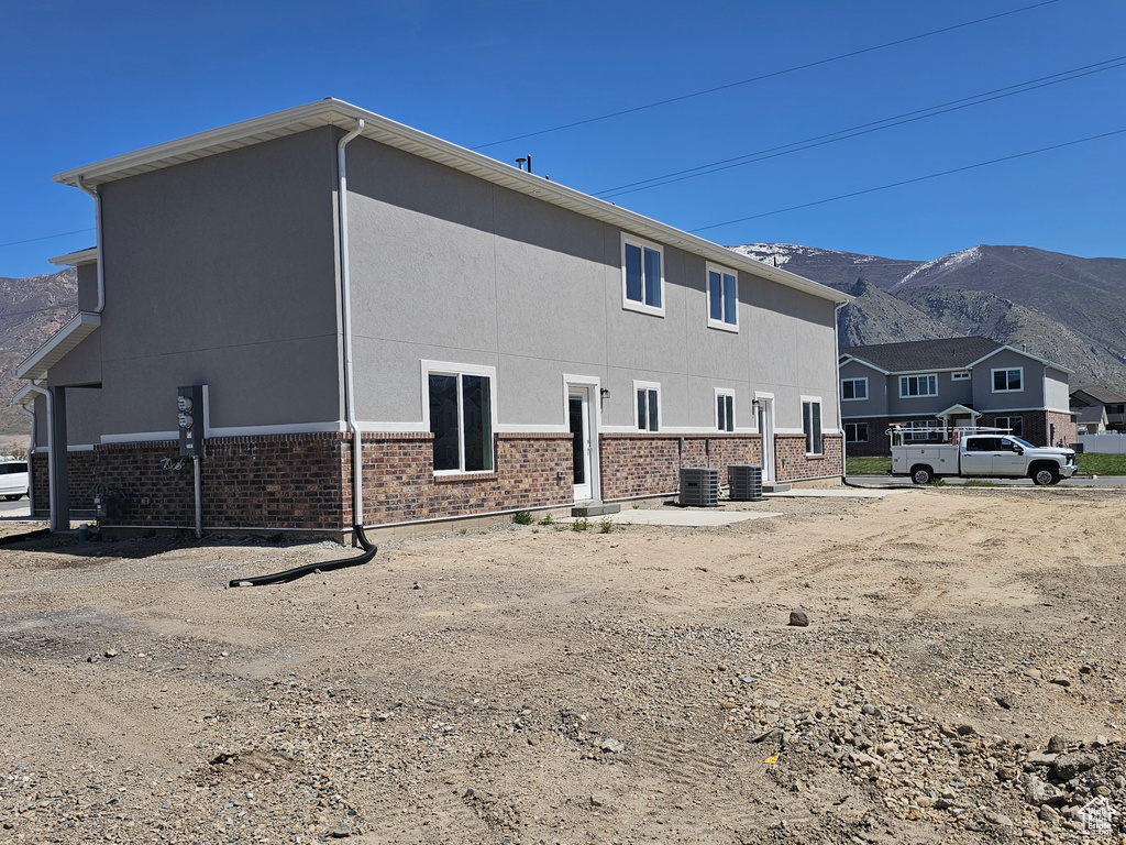 Back of house featuring central air condition unit, a mountain view, and brick siding