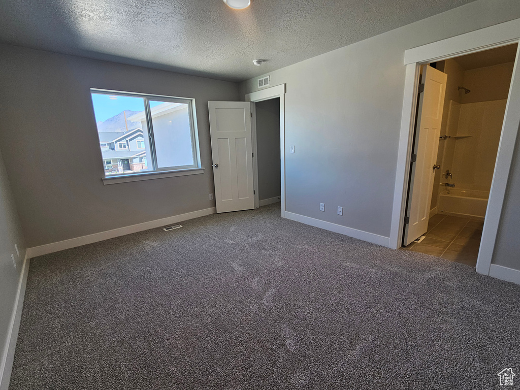 Unfurnished bedroom with carpet, a textured ceiling, baseboards, and visible vents