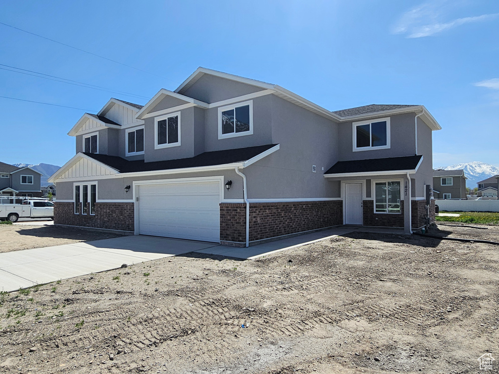 View of front facade with an attached garage, stucco siding, brick siding, and concrete driveway