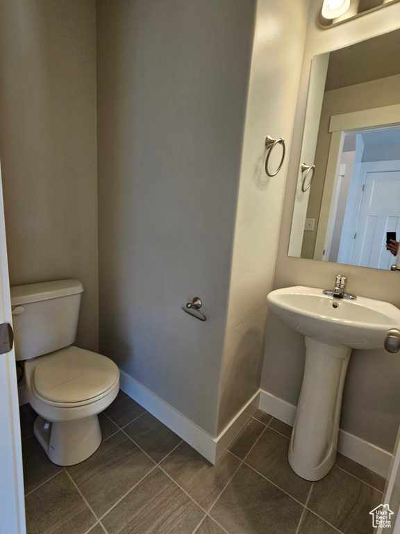 Half bath with tile patterned flooring, baseboards, a sink, and toilet