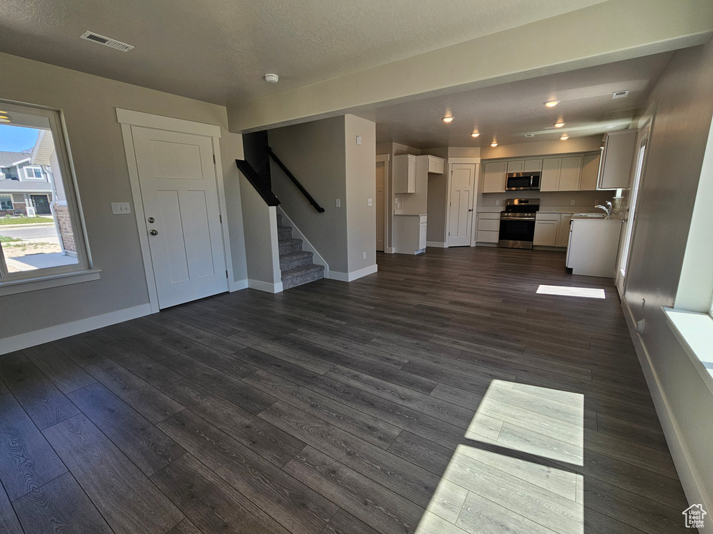 Unfurnished living room with stairway, visible vents, and baseboards