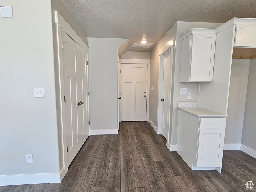Hall with baseboards, visible vents, a textured ceiling, and dark wood-style floors