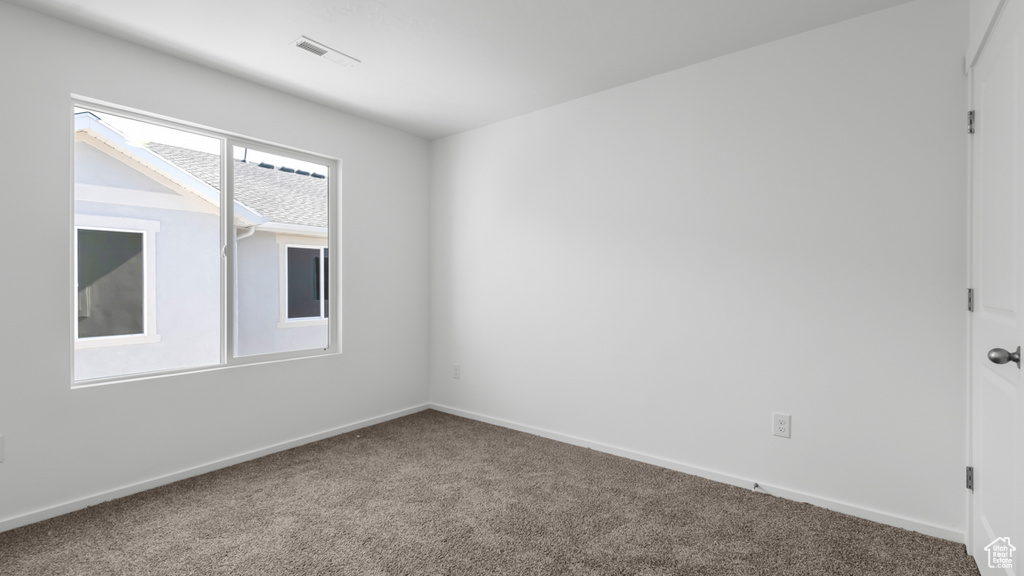 Carpeted spare room featuring baseboards and visible vents