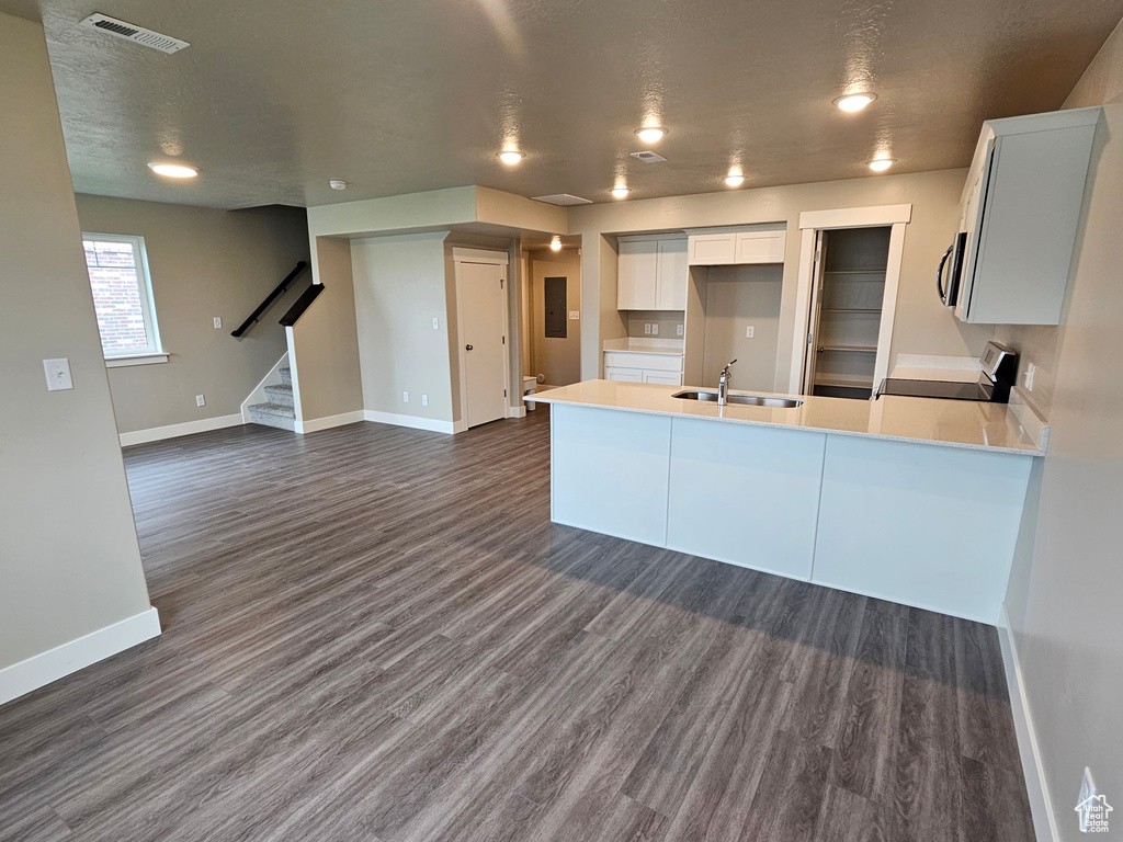 Kitchen with a sink, a peninsula, stainless steel microwave, baseboards, and visible vents