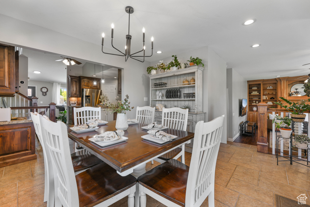 Dining room with ceiling fan with notable chandelier, recessed lighting, baseboards, visible vents, and stone tile flooring