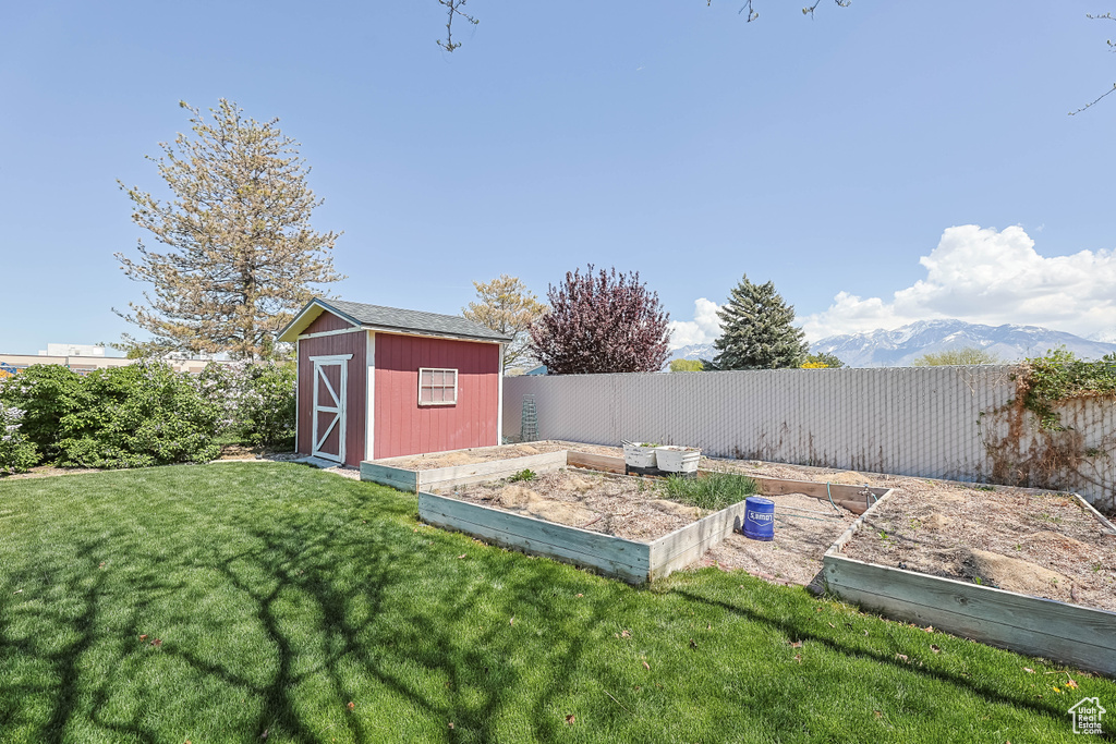 View of yard featuring a fenced backyard, an outdoor structure, a garden, and a shed