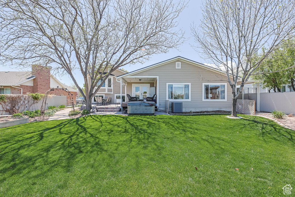 Back of house featuring central AC, an outdoor living space, a lawn, and fence