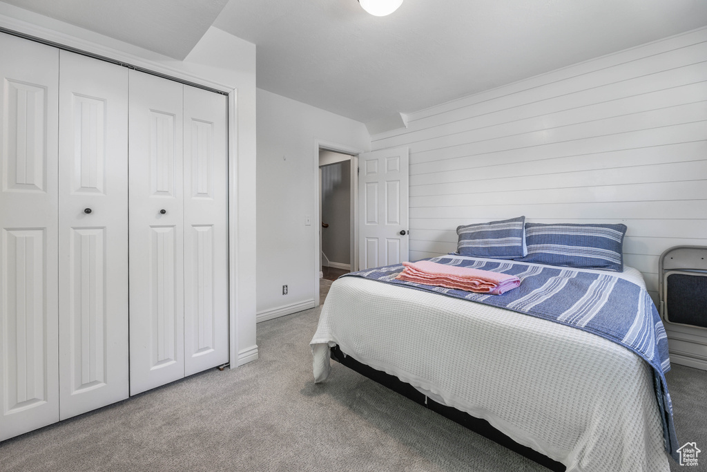 Bedroom featuring carpet flooring, baseboards, wood walls, and a closet