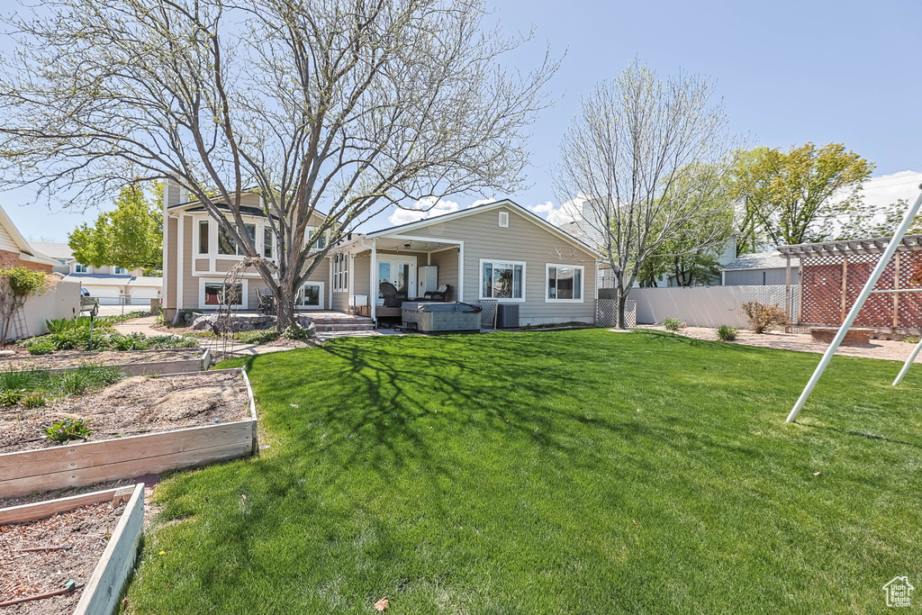Rear view of property featuring fence, a yard, a garden, and cooling unit