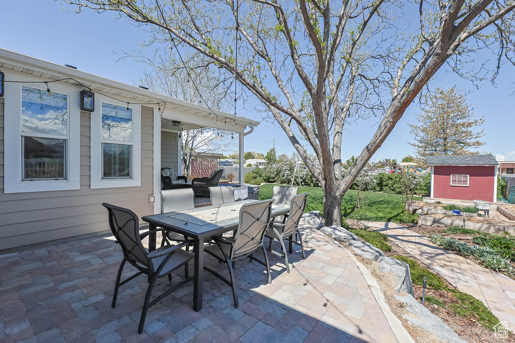 View of patio featuring outdoor dining area, an outdoor structure, and a storage unit