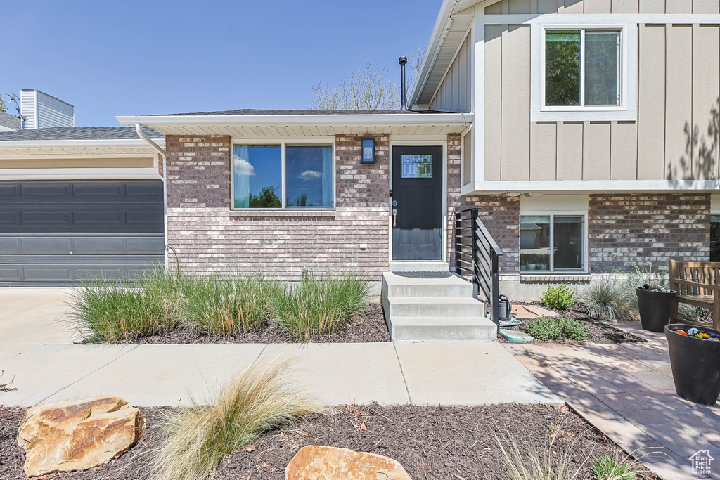 View of front of house with board and batten siding, brick siding, an attached garage, and driveway