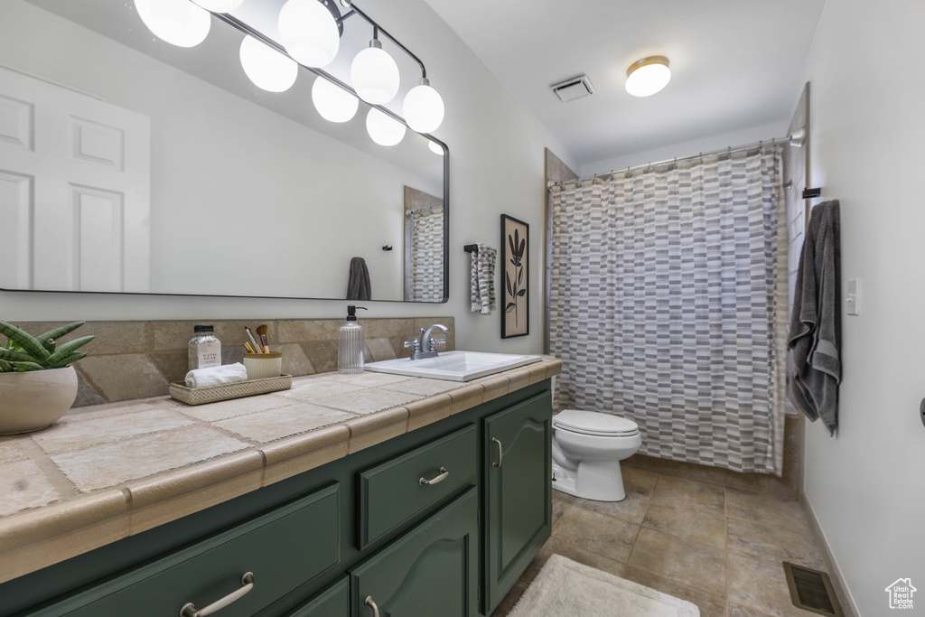 Full bathroom featuring vanity, stone finish floor, toilet, and visible vents