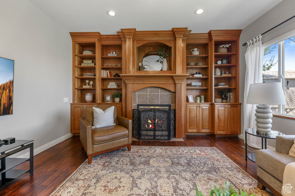 Living room featuring a tiled fireplace, recessed lighting, baseboards, and dark wood-style floors