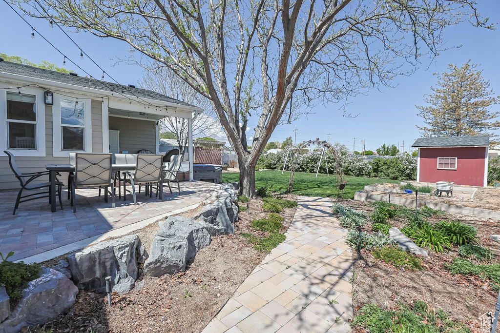 View of yard featuring a patio, outdoor dining area, a storage shed, and an outdoor structure