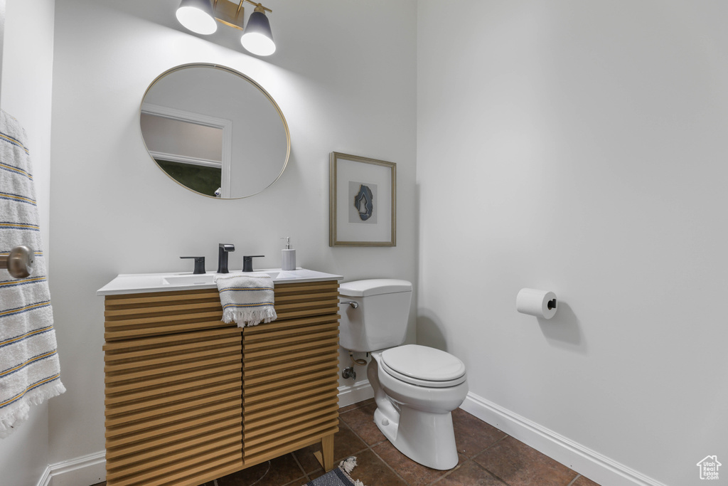Bathroom featuring toilet, baseboards, tile patterned floors, and vanity