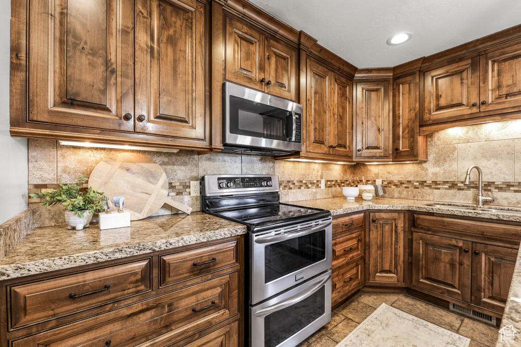 Kitchen featuring a sink, decorative backsplash, stainless steel appliances, and visible vents