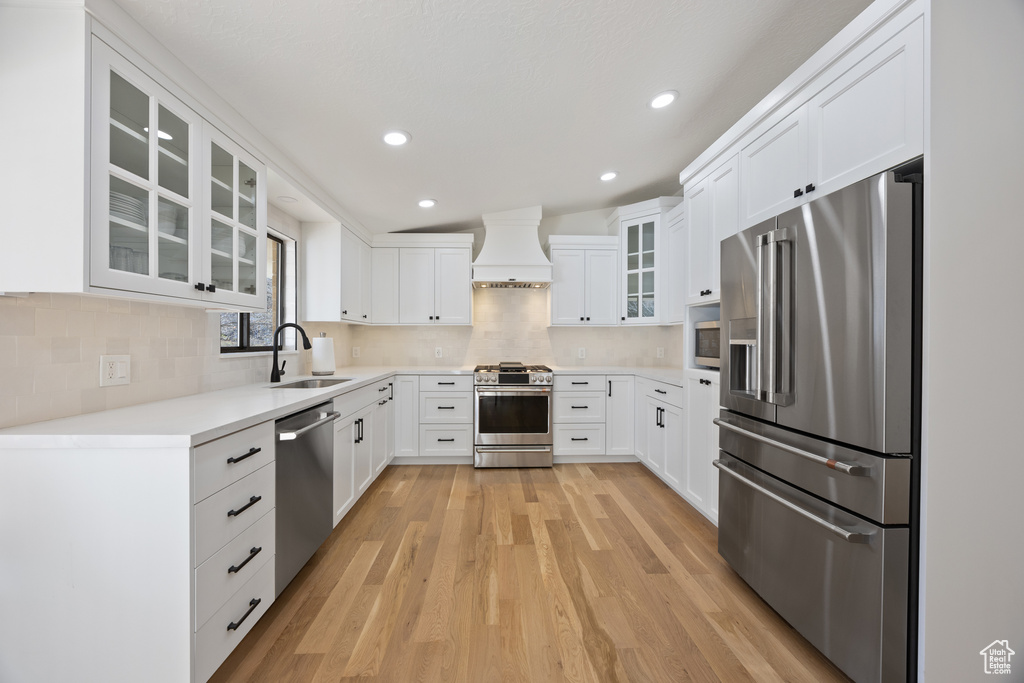 Kitchen with premium range hood, recessed lighting, a sink, light wood finished floors, and stainless steel appliances