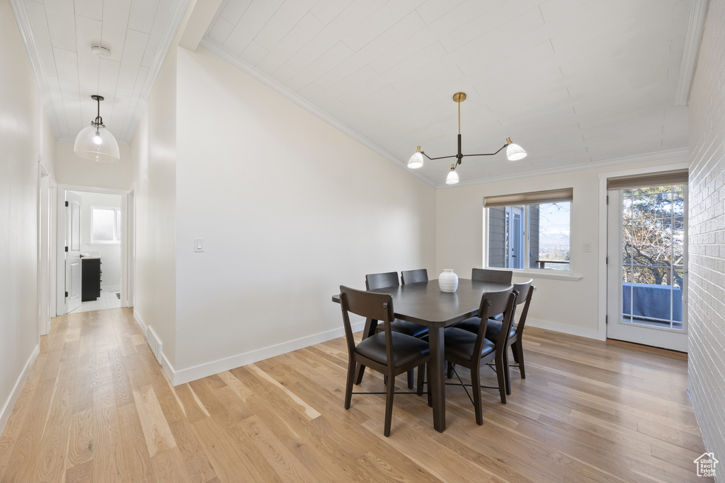 Dining room with crown molding, an inviting chandelier, and light wood-style flooring