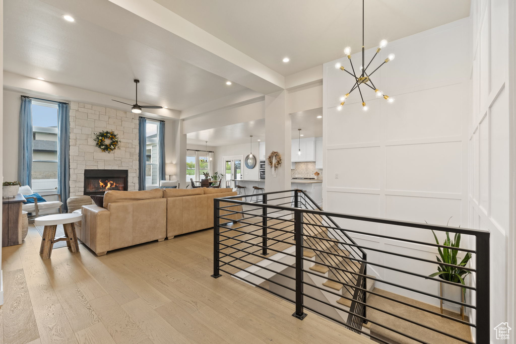 Interior space with recessed lighting, wood finished floors, a decorative wall, ceiling fan with notable chandelier, and a stone fireplace