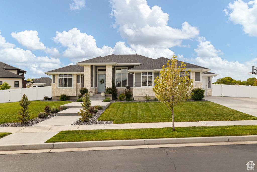 Prairie-style house featuring a front yard, stone siding, and fence
