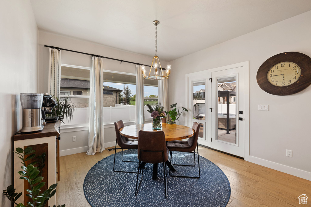 Dining room with light wood-type flooring, a notable chandelier, and baseboards