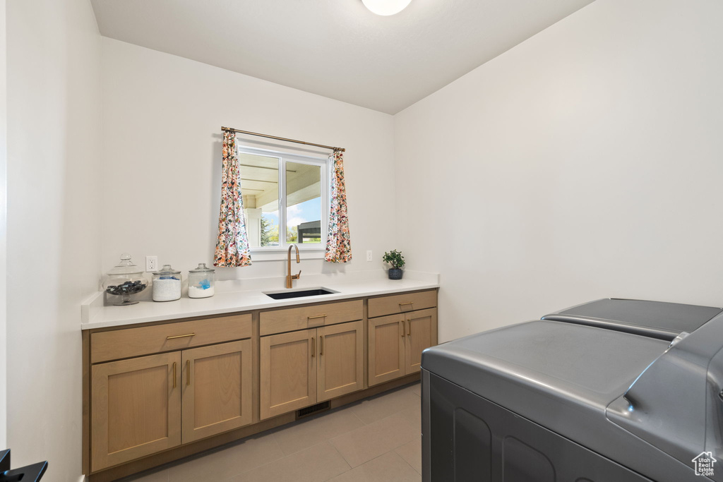 Washroom with light tile patterned floors, cabinet space, separate washer and dryer, and a sink