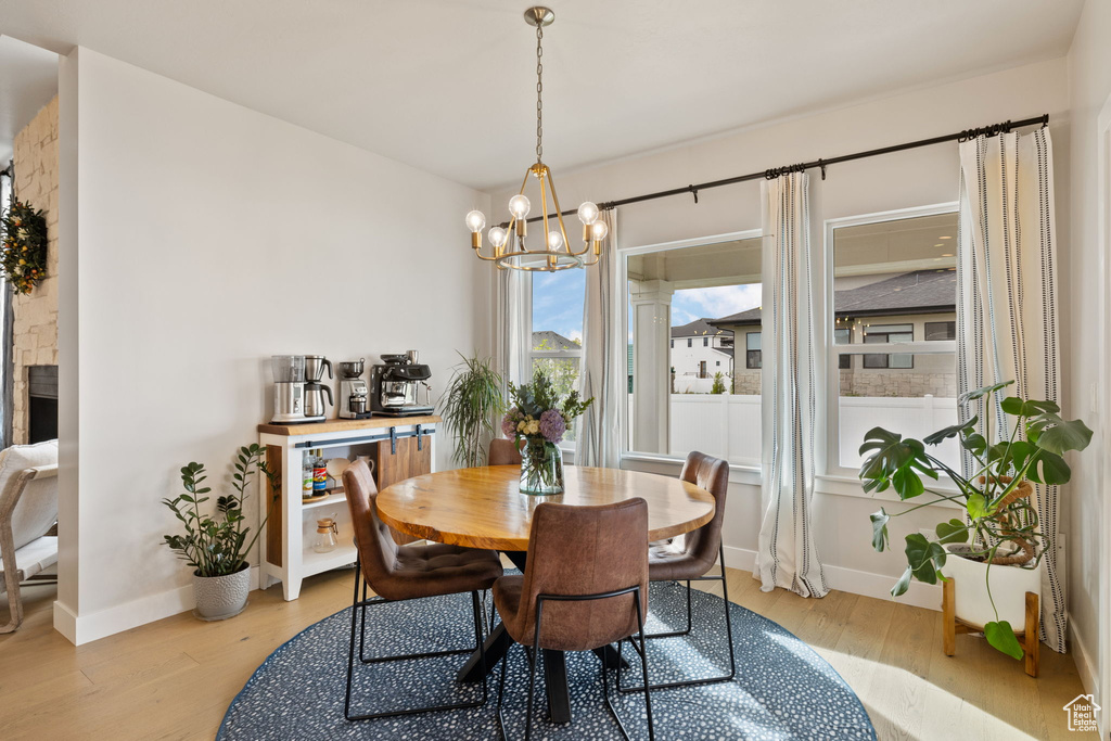 Dining space featuring light wood-type flooring, a notable chandelier, and baseboards