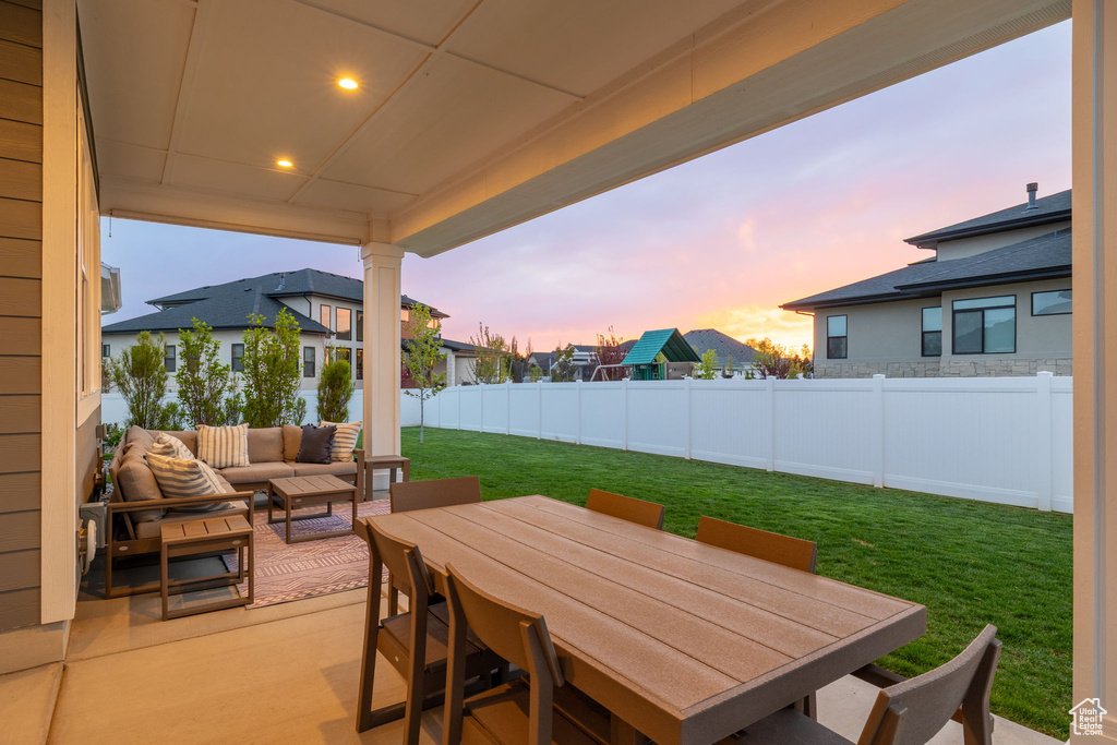 Patio terrace at dusk featuring outdoor lounge area, outdoor dining area, a yard, and a fenced backyard