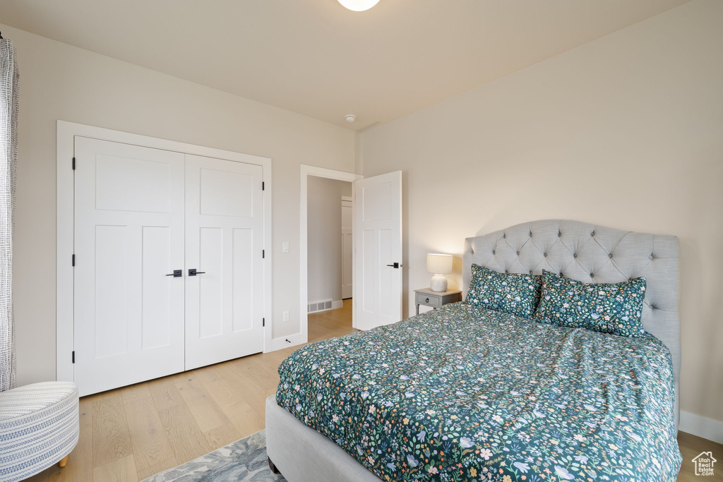 Bedroom with baseboards, wood finished floors, and a closet