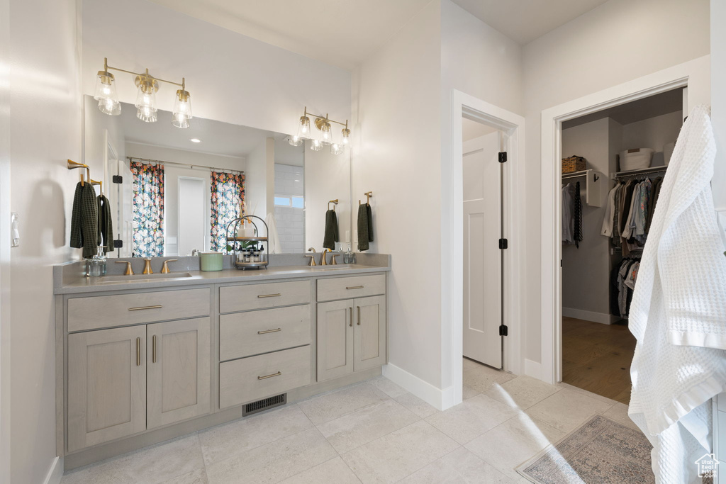 Bathroom featuring double vanity, visible vents, baseboards, tile patterned flooring, and a walk in closet