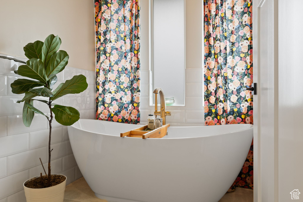 Bathroom with a wainscoted wall, tile walls, and a soaking tub