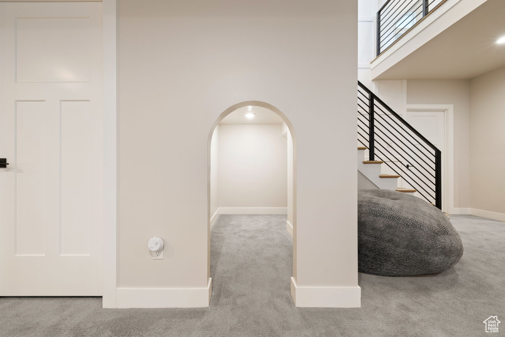 Staircase with a high ceiling, baseboards, carpet flooring, and arched walkways