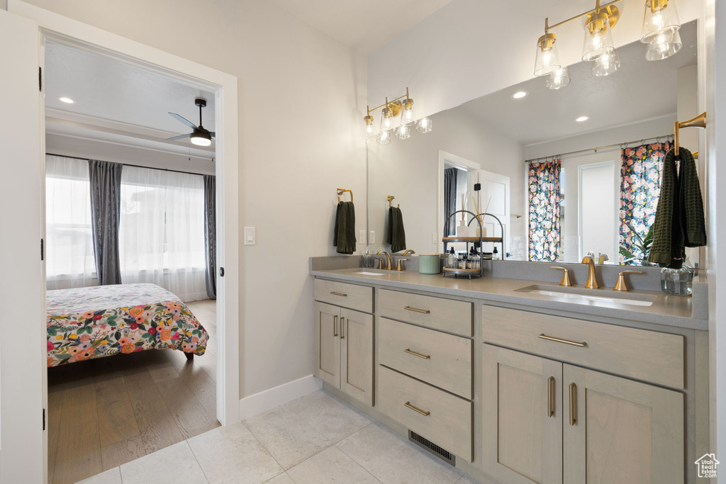 Ensuite bathroom with double vanity, a ceiling fan, baseboards, and a sink