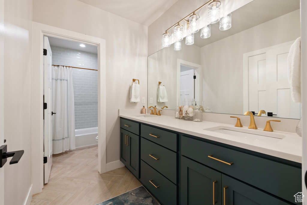 Full bathroom with shower / bath combo with shower curtain, double vanity, a sink, and baseboards