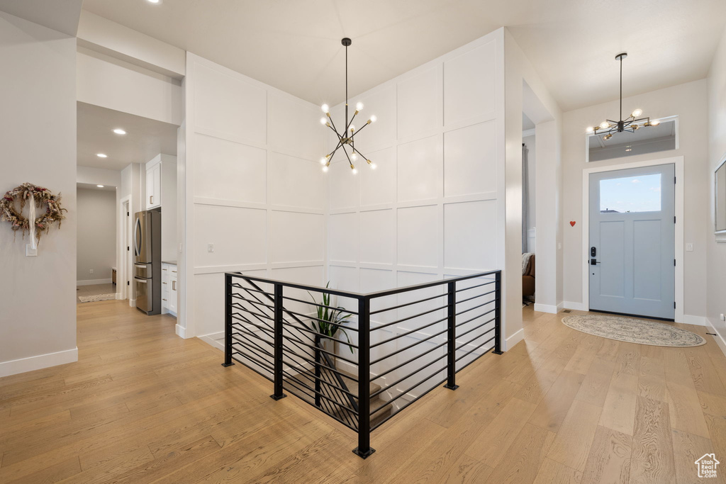 Entryway featuring baseboards, light wood-type flooring, a notable chandelier, and a decorative wall