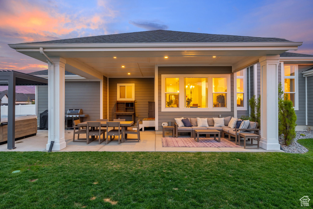 Back of house featuring a patio area, a yard, an outdoor living space, and a hot tub