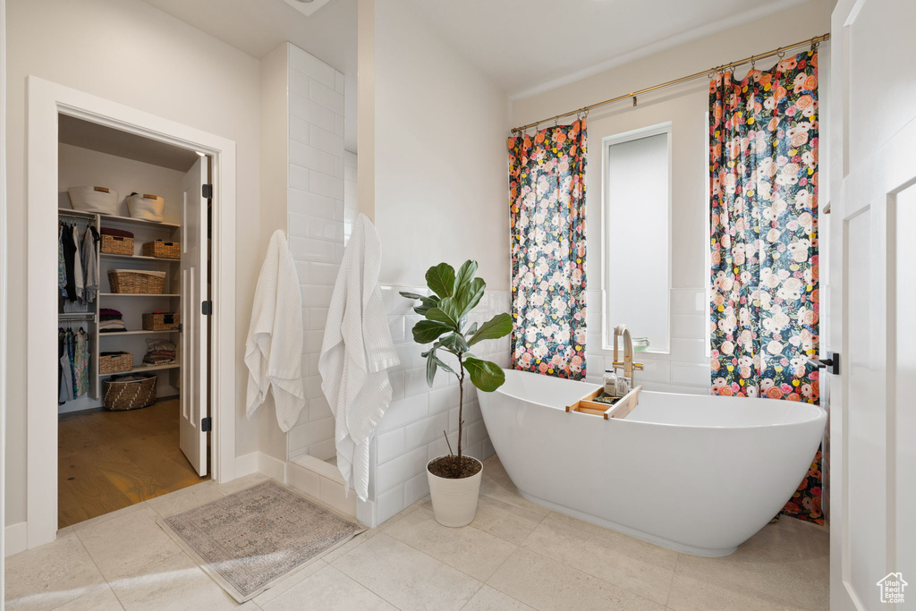 Bathroom featuring a sink, a spacious closet, a soaking tub, and a shower with shower curtain
