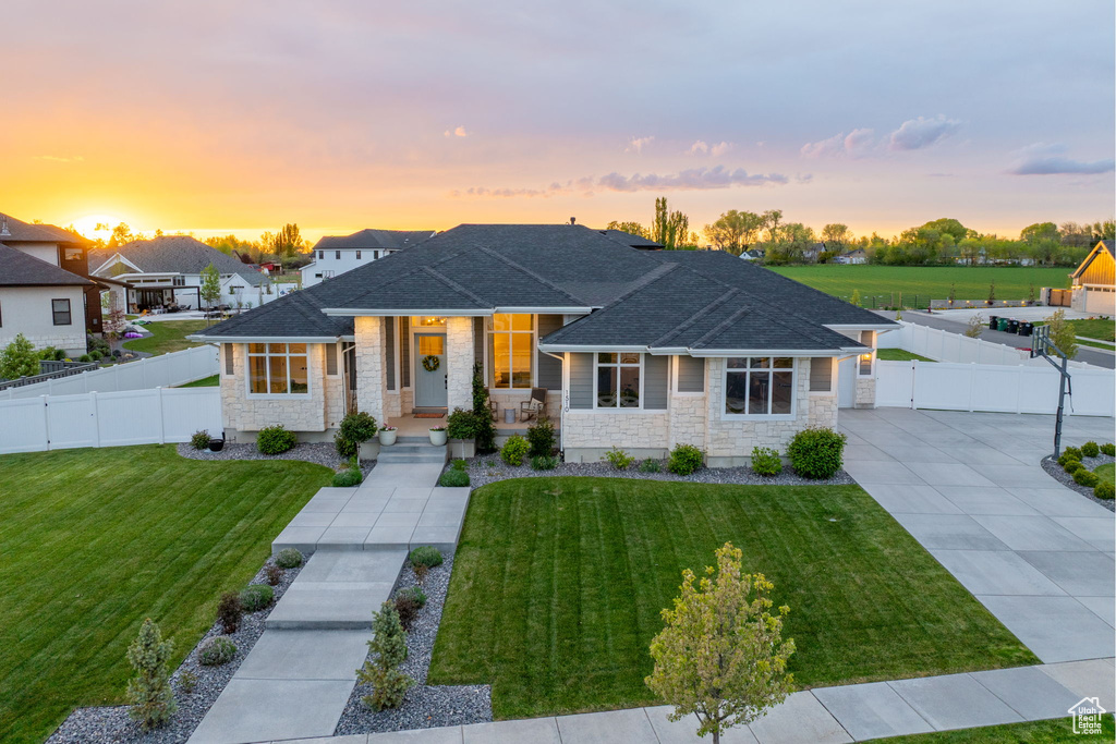 View of front of house featuring fence, a front lawn, and stone siding