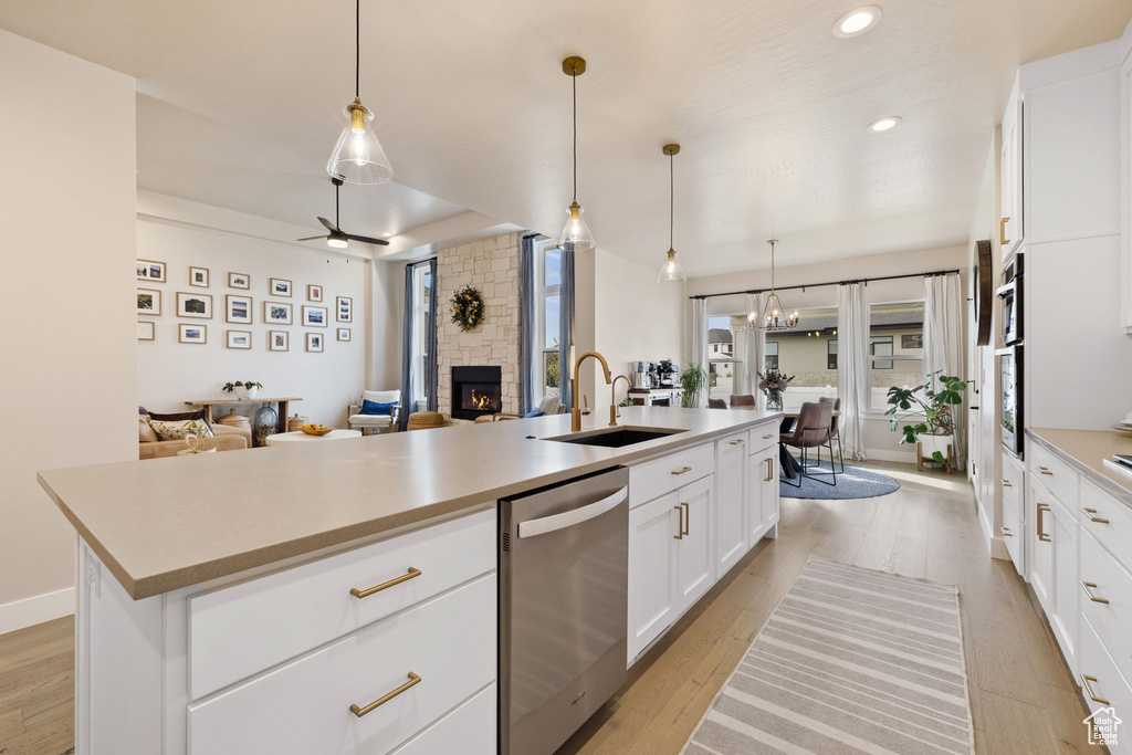 Kitchen with a sink, dishwasher, a stone fireplace, and open floor plan