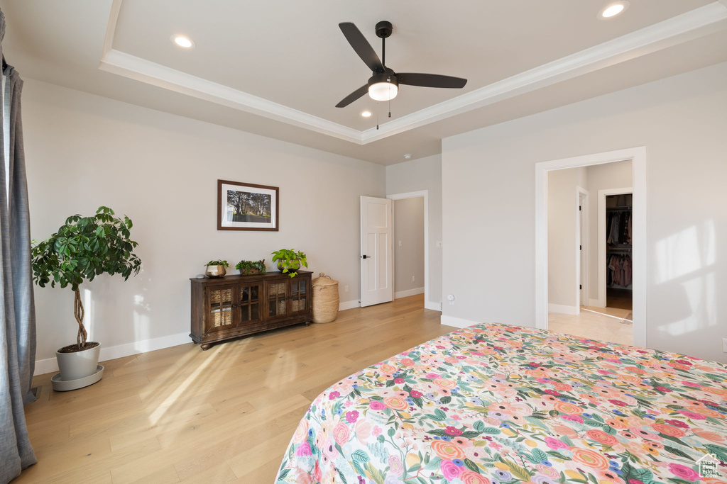 Bedroom with crown molding, a raised ceiling, and light wood-style floors