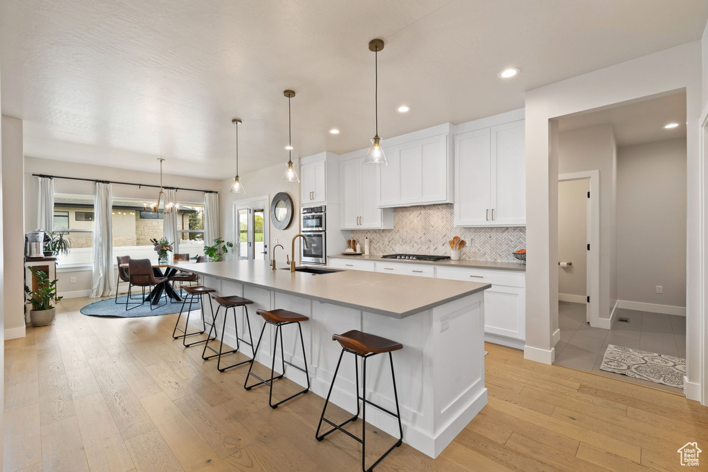 Kitchen featuring a breakfast bar, backsplash, a sink, baseboards, and gas cooktop