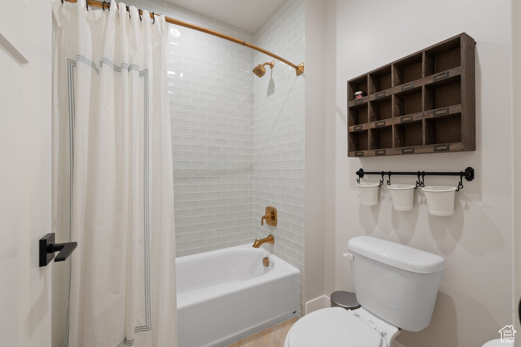 Bathroom with shower / tub combo, toilet, and wood finished floors