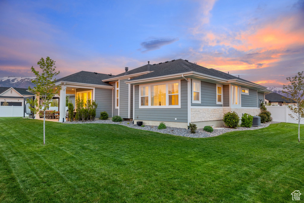 Prairie-style house featuring a front lawn, a patio, stone siding, and fence