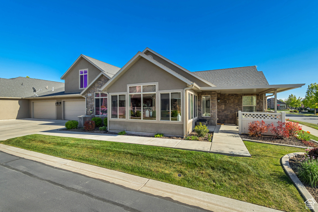 View of front of property with a front lawn, stucco siding, and stone siding