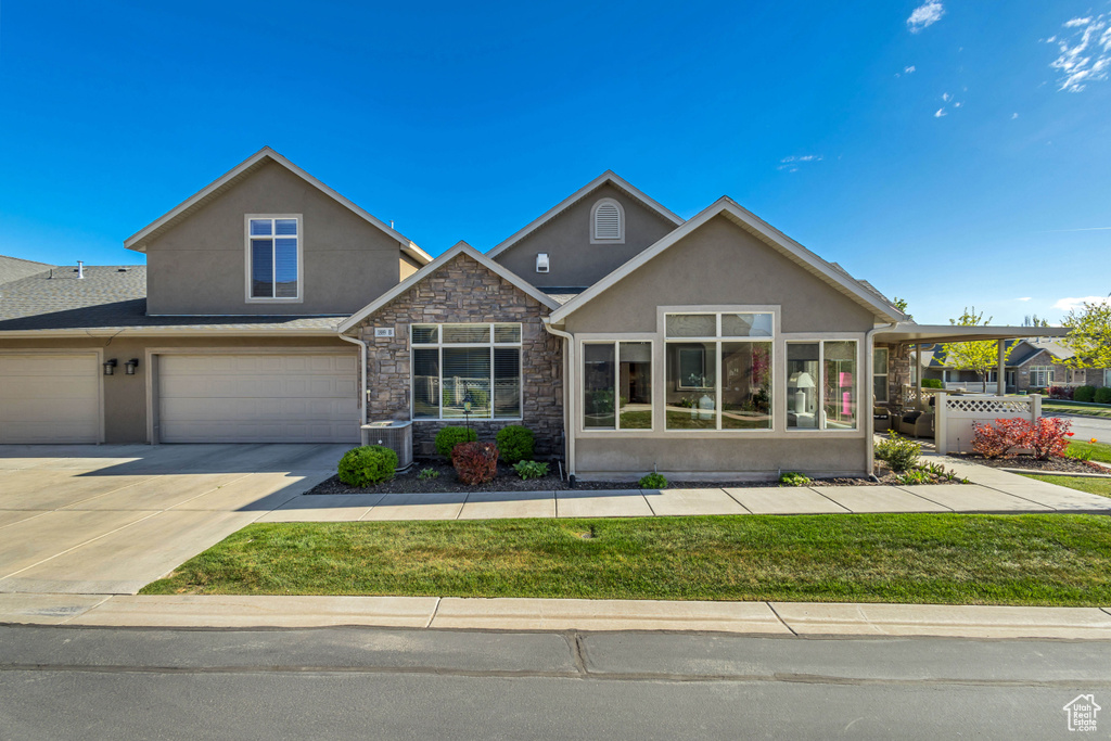 View of front of property with central AC unit, concrete driveway, an attached garage, stone siding, and stucco siding