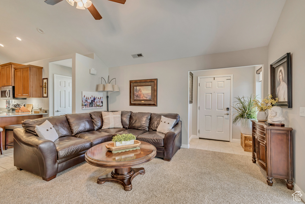 Living area with a ceiling fan, visible vents, light colored carpet, light tile patterned floors, and lofted ceiling