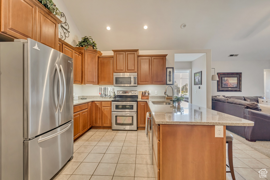 Kitchen with a sink, a peninsula, open floor plan, stainless steel appliances, and light tile patterned flooring