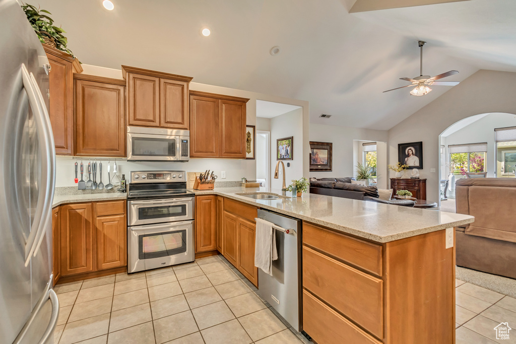 Kitchen featuring appliances with stainless steel finishes, a sink, light tile patterned floors, a peninsula, and open floor plan